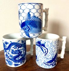 three blue and white mugs sitting on top of a wooden table