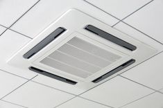 an air conditioner mounted to the ceiling in a room with white tiles on it