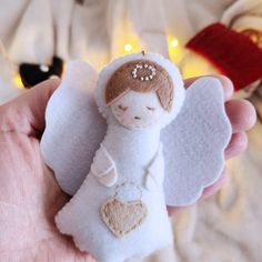 a hand holding a small felt angel ornament