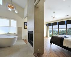 a bedroom with a large bed and a bathtub in the corner next to a fireplace