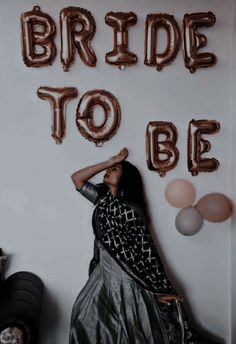 a woman standing in front of balloons that say bride to be