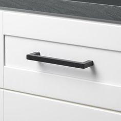 a black handle on a white cabinet drawer