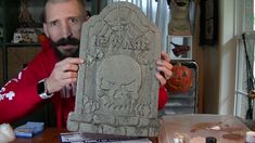 a man holding up a stone carving in front of his face