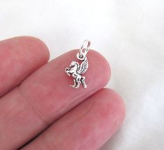 This Sterling Silver tiny charm is a Pegasus design 8 x 10mm (5/16 x 3/8") without bail. There is a lot of detail for such a tiny charm. The coin shown in the picture is for size comparison. Weight is 0.4 grams. This item is stamped "ster".   The open "jump ring" attached to the charm is 19 gauge 6.3mm O.D. sterling silver. For European bracelets, message me for a 7.3mm ring. _______________________    To combine shipping: Enter items in "ADD TO CART", then proceed to checkout. This item is shipped in a gift box!  *The above measurements can be used to draw a square or rectangle for a  reference to the item size.  Sterling Silver is a metal alloy that contains 92.5% silver and 7.5% other metals to increase its strength. These trace metals help cause the sterling silver to tarnish due to va Keepsake Ideas, Silver Cleaner, Tiny Charm, Fine Jewellery Necklace, Sterling Silver Charm, Charm Jewelry, Link Bracelets, Sterling Silver Jewelry, Jewelry Necklace Pendant