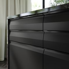 a close up of a black dresser near a window