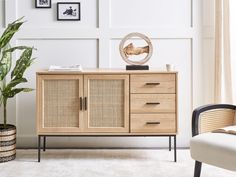 a living room with a chair, sideboard and potted plant in the corner