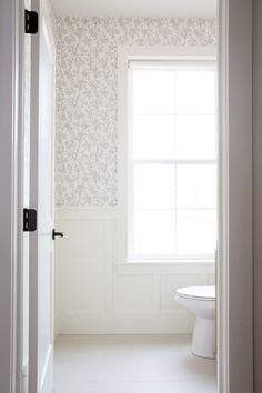 a white toilet sitting next to a window in a bathroom