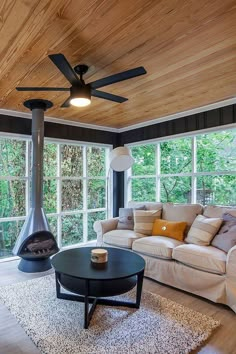 a living room filled with furniture and a fire place in front of a windowed wall