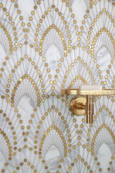 an ornate white and gold wallpaper with a golden handle on the doorknob