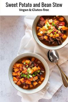 two bowls of sweet potato and bean stew on top of a white cloth with spoons