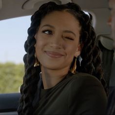 a woman sitting in the back seat of a car with braids on her hair