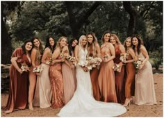 a group of women standing next to each other in long dresses and holding bouquets