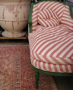 a striped chair sitting on top of a rug next to a large potted plant