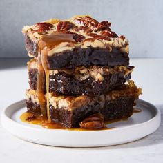 a stack of brownies with pecans and caramel drizzle on top