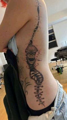 a woman with a skeleton tattoo on her back and shoulder is looking at the camera