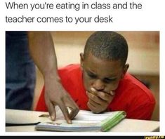 a young boy sitting at a desk with his hand on the book and looking down