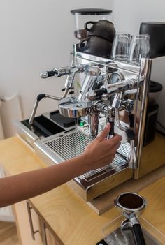 a person is using a coffee machine to make some espresso in front of them