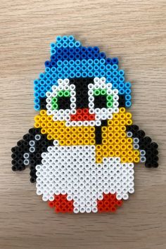 an image of a penguin made out of legos on a wooden table with beads