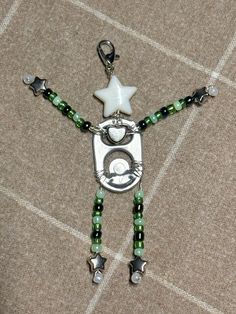 a green and white beaded necklace with a silver star on the clasp, beads and charms attached to it