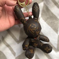 a hand holding a brown and black keychain with a small animal on it