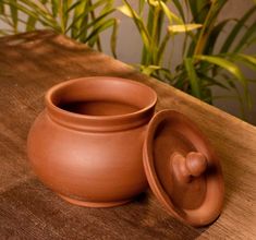 a clay pot sitting on top of a wooden table next to a green planter