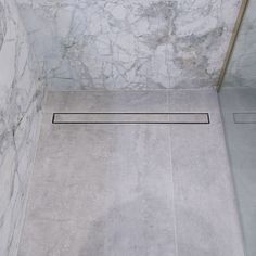 a bathroom with marble walls and flooring in the shower area is seen from above