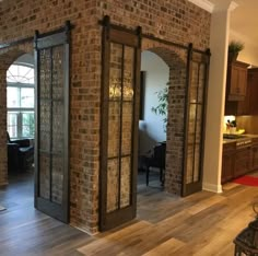 an open living room and dining area with brick walls, wood floors and glass doors