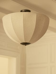 a light fixture hanging from the ceiling in a room with white walls and trimmings