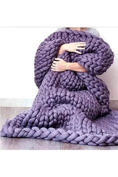 a woman wrapped in a purple blanket with her hands on her chest and arms crossed