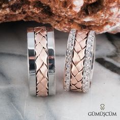 two wedding bands with diamonds on them sitting next to a rock