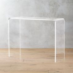 an acrylic table sitting on top of a wooden floor next to a wall