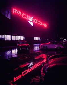 three cars parked in front of a porsche dealership with neon lights on the side