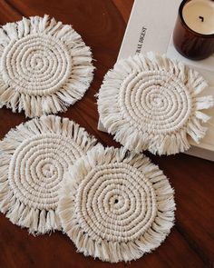 three white round doilys sitting on top of a table next to a candle