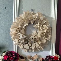 a wreath is hanging on the wall next to flowers