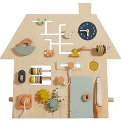 a wooden toy house with various items on the floor and around it, including a clock