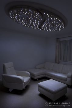 a living room with white furniture and lights on the ceiling