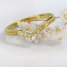 a gold ring with a diamond sitting on top of it next to some white flowers