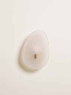 a white object with a brown spot in the center on a white surface, it appears to be an egg or something