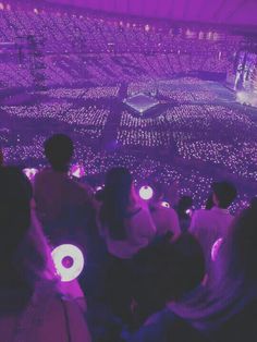 people are sitting in the middle of a large room with purple lights on their backs