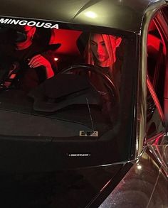 two women sitting in the driver's seat of a car with red lights on