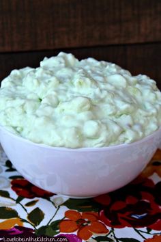 a white bowl filled with food sitting on top of a floral table cloth next to a knife