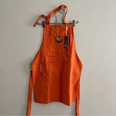 an orange apron hanging on a white wall