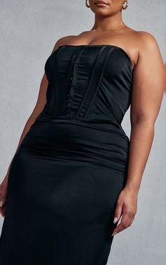 a woman in a black dress posing for the camera with her hands on her hips