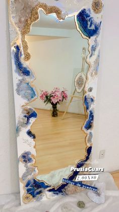 a mirror that is sitting on top of a wooden floor next to a vase with flowers in it