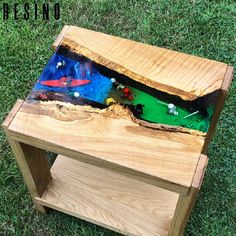 a small wooden table that is on the grass with toys in it's hole