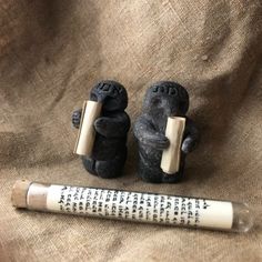 two small figurines sitting next to a tube of toothpaste on a brown cloth