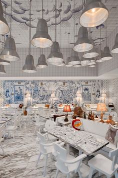 the interior of a restaurant with white tables and chairs, chandeliers hanging from the ceiling