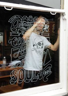 a man standing in front of a store window with his hand up to his face