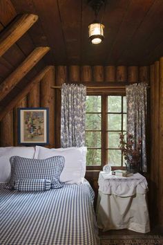 a bed sitting under a window in a bedroom next to a wooden wall and ceiling