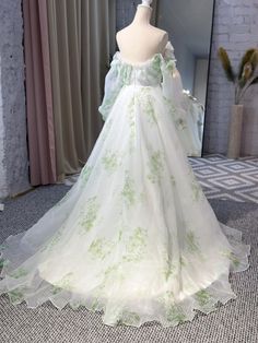 a white dress with green flowers on it is sitting on a mannequin in front of a mirror